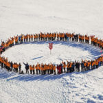 Passengers form a circle at the North Pole on the ice pack. North Pole travel Cruise to North Pole