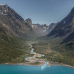 Aerial view of a river canyon with step mountain peaks on either side of winding river. Landscape of Greenland in the Arctic. Greenland cruise Greenland holiday