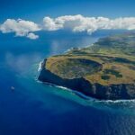 Aerial view of Easter Island with cliff wall facing ocean with large crater in the hill top. Easter Island Cruise