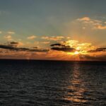 Sunset of golden yellow peaking through the clouds on a horizon of nothing but the Atlantic Ocean. Travel Atlantic Ocean
