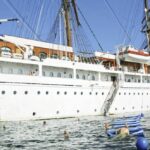 Passengers swim off the side of white sail ship in middle of ocean. Atlantic ocean cruise
