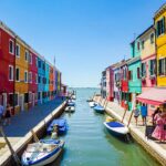 Colorful buildings on either side of small waterway in Burano town of Italy. Venice cruise