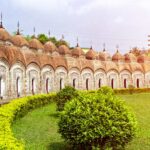 View of Shiva Temple in Kalna India. Wall of symmetrical towers with white and gold detailed with grass and bush garden. Itinerary Ganges River - Indian river cruise.