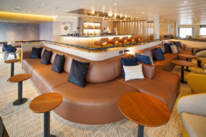 Panorama lounge and bar aboard the polar expedition ship - Ultramarine. A comfortable room of luxury leather couches and wooden coffee tables with material single seats as well.