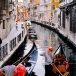 Water canals of the Venice waterways with classic Gondolas in foreground and the twisting waterway making its way through the buildings on the water edge. Venice cruise