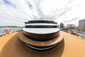 The observation deck of the World Explorer ship - designed to travel the polar regions of Antarctic and Arctic. Looking back towards the back of the ship, one sees the bridge of ship as well as the sleek wooden wraparound viewing deck with a wooden bench running down the middle.